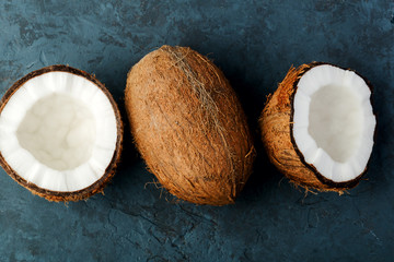health content, composition on dark blue table made of stone, coconut halves, whole coconut, top view