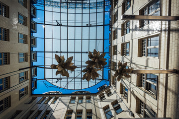 passage in leipzig with half-open glass ceiling with blue sky and ceiling-hanging floral artworks