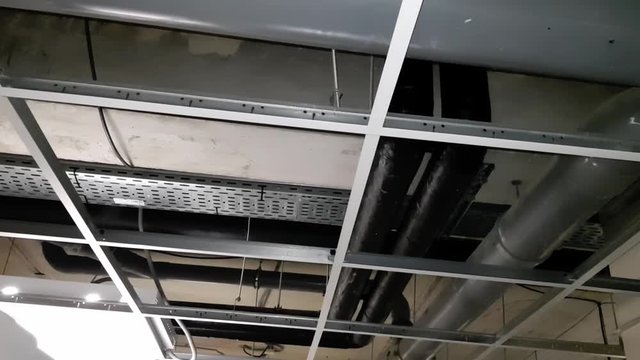 Rows of metal conduit pipes installed to the ceiling of a building.