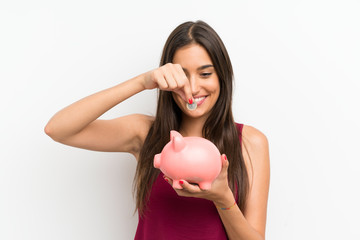 Young woman over isolated white background holding a big piggybank