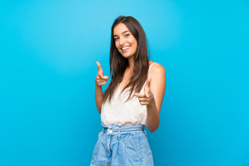 Young woman over isolated blue background pointing to the front and smiling