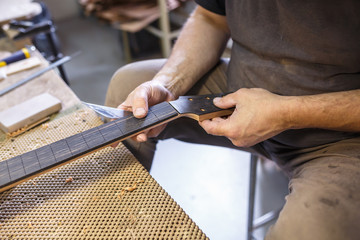 grinding and polishing the guitar wooden neck. hand-made musical instruments