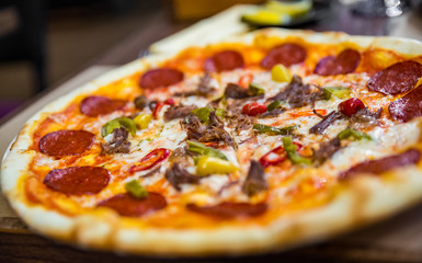 Pizza with Mozzarella cheese, salami, Tomatoes, hot pepper, Spices. Italian pizza on wooden table background