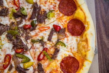 Pizza with Mozzarella cheese, salami, Tomatoes, hot pepper, Spices. Italian pizza on wooden table background