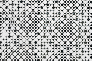 Black and white random dots pattern. Porous abstract white background with circles of different diameters. White metal mesh texture with uneven holes.