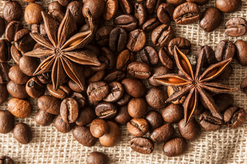 Roasted coffee beans and spice badian on a background of burlap.