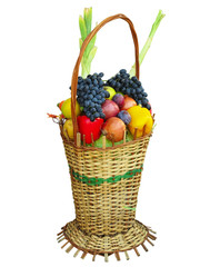 Wicker basket filled with colorful organic vegetables fresh harvest plums, grapes and apples isolated