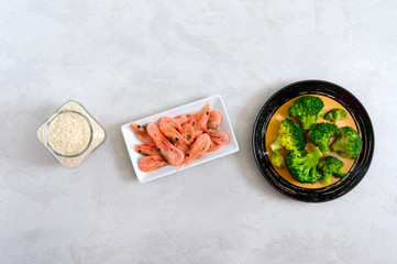 Boiled broccoli, shrimp, rice on a concrete background. Healthy eating concept. Sports diet. A set of ingredients for proper nutrition. Healthy lifestyle. Copy space. Top view.