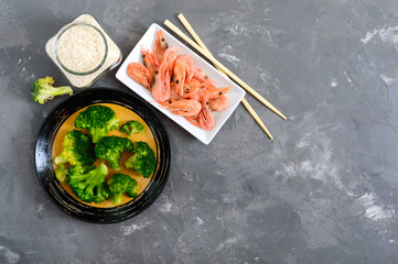 Boiled broccoli, shrimp, rice on a concrete background. Healthy eating concept. Sports diet. A set of ingredients for proper nutrition. Healthy lifestyle. Copy space. Top view.