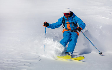 A skier on the slope. Out-of-piste skiing. Good winter day, ski season. professional rider in bright blue-orange ski suit and original hat on his head. high resolution photo quality