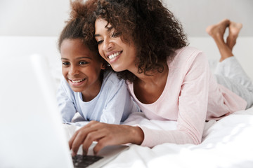 Fototapeta premium Smiling young mother and her little daughter wearing pajamas