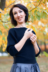 Beautiful elegant woman standing and posing in a city park in autumn