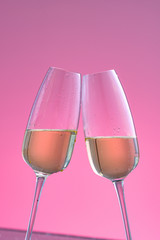 two glasses of sparkling wine on a pink background