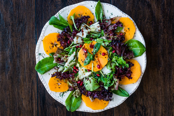 Persimmon Fruit Salad with Pomegranate, Lollo Rosso Lettuce, Rocket Arugula or Rucola and Mint Leaves.
