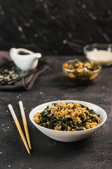 Wok rice with seaweed in a white plate with chopsticks and soy sauce.