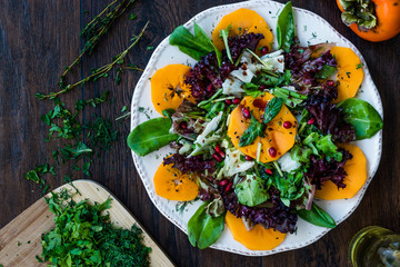 Persimmon Fruit Salad with Pomegranate, Lollo Rosso Lettuce, Rocket Arugula or Rucola and Mint Leaves.