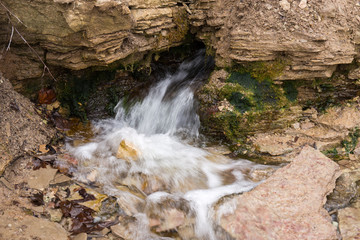 Fototapeta premium Natural textures. The spring flows from a steep rocky hillside. Early spring. Izborsk, Pskov region, Russia.