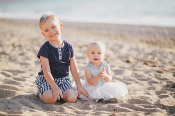 Little brother and sister posing near sea at beach