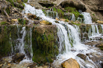 Fototapeta na wymiar Natural textures. The spring flows from a steep rocky hillside. Early spring. Izborsk, Pskov region, Russia.