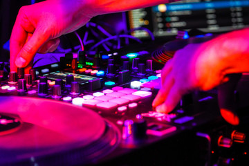 DJ plays a party in a nightclub,  DJ hands on a sound mixer, selected focus