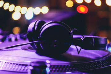 DJ headphones on a vinyl player in a dark nightclub, selective focus