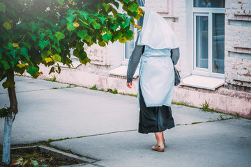 A nun walks on the sidewalk of an old city