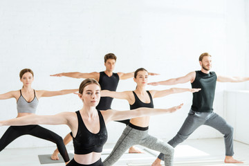 five young people practicing yoga in warrior II pose