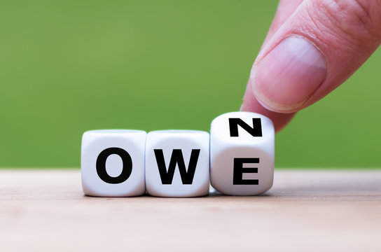 Hand turns a dice and changes the word "owe" to "own".