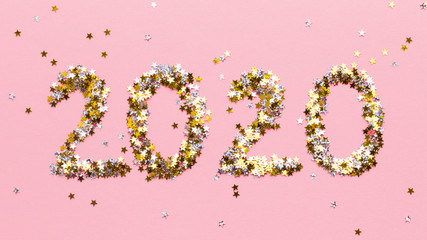 New Year 2020 concept of gold confetti on pink background