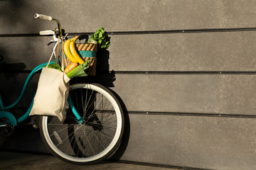 Retro bicycle with fresh fruits and vegetables over gray wall