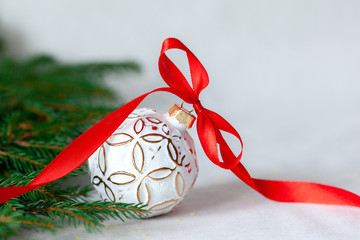 Christmas holidays composition with white ball and red ribbon on light background with copy space