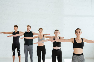 Obraz premium five young men and women practicing yoga in mountain open arm pose