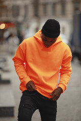 Handsome African man model wearing empty bright orange hoodie in city - 301990332