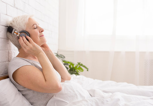 Tranquil Senior Lady Listening To Audiobook In Bed