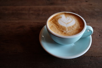 Cappuccino or latte with frothy foam, blue coffee cup top on wooden coffee shop background