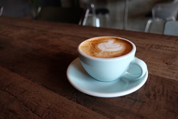 Cappuccino or latte with frothy foam, blue coffee cup top on wooden coffee shop background