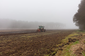 Landwirtschaft in der kalten Jahreszeit Traktor pflügt im Morgennebel Herbstwetter Herbstmorgen Landmaschine pflügen wintermorgen einsamer landwirt acker Ackerfläche ackerboden feldarbeit schicht 