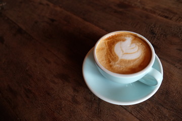 Cappuccino or latte with frothy foam, blue coffee cup top on wooden coffee shop background