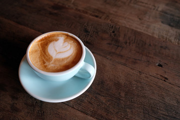 Cappuccino or latte with frothy foam, blue coffee cup top on wooden coffee shop background