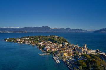 Fototapeta na wymiar Unique view. Aerial photography, the city of Sirmione on Lake Garda north of Italy. In the background is the Alps in the snow. Resort place. Aerial view. Autumn-winter season