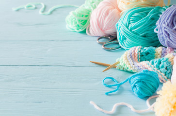 Knitted colored striped fabric. Yarn for knitting pastel colors. Blue painted wood background.