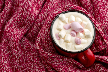 top view warming drink with marshmallows on a red knitted sweater background