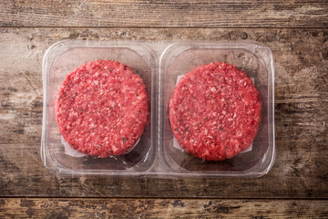 burger meat packaged in plastic on wooden table. Top view