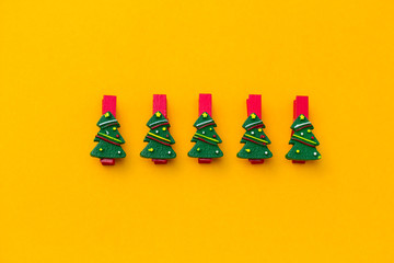 top view flat lay festive red clothespins decorated with christmas tree on a vibrant yellow background - obrazy, fototapety, plakaty