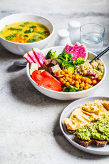 Vegan lunch. Buddha bowl with tofu, chickpeas and quinoa, lentil soup and toasts on a gray background.