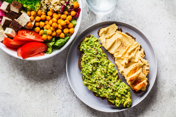 Buddha bowl with quinoa, chickpeas, tofu salad and toast with hummus and guacamole. Healthy vegan food concept.