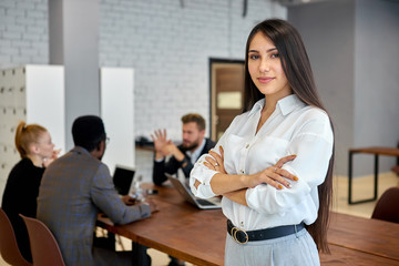 Personable and confident young woman brunette with long hair look at camera. Businesswoman in white shirt posing in office