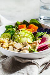 Quinoa salad with tofu, avocado and vegetables in white bowl. Vegan breakfast.