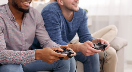 Two mates holding joysticks, playing video games