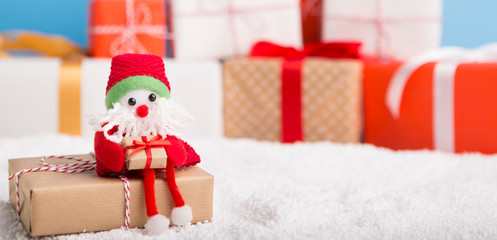 Toy Santa sitting on wrapped present box and waiting for orders